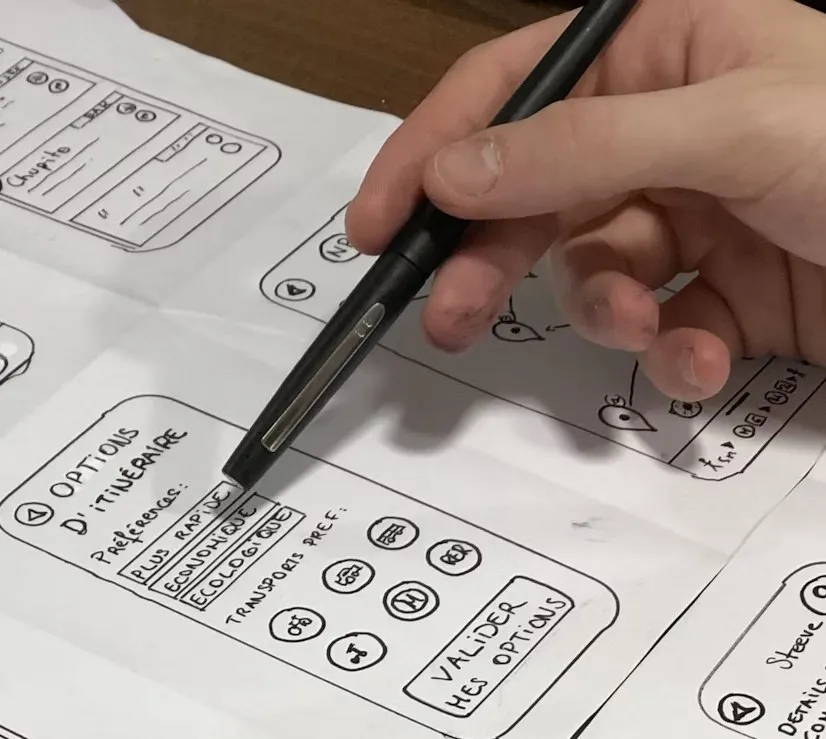 A hand sketching mobile screens with a pen