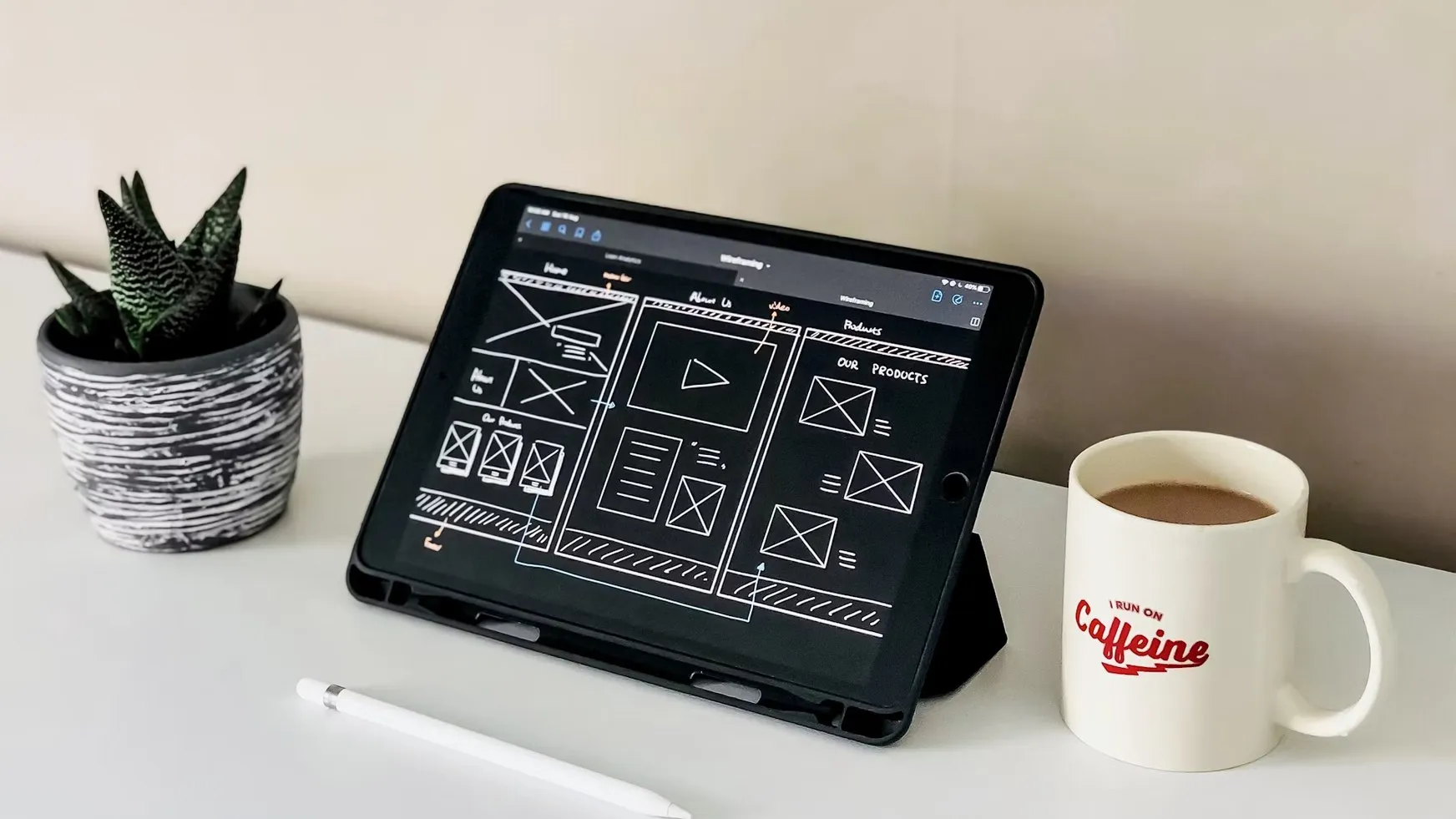 A ProUX wireframe on a tablet next to a cactus and a coffee mug
