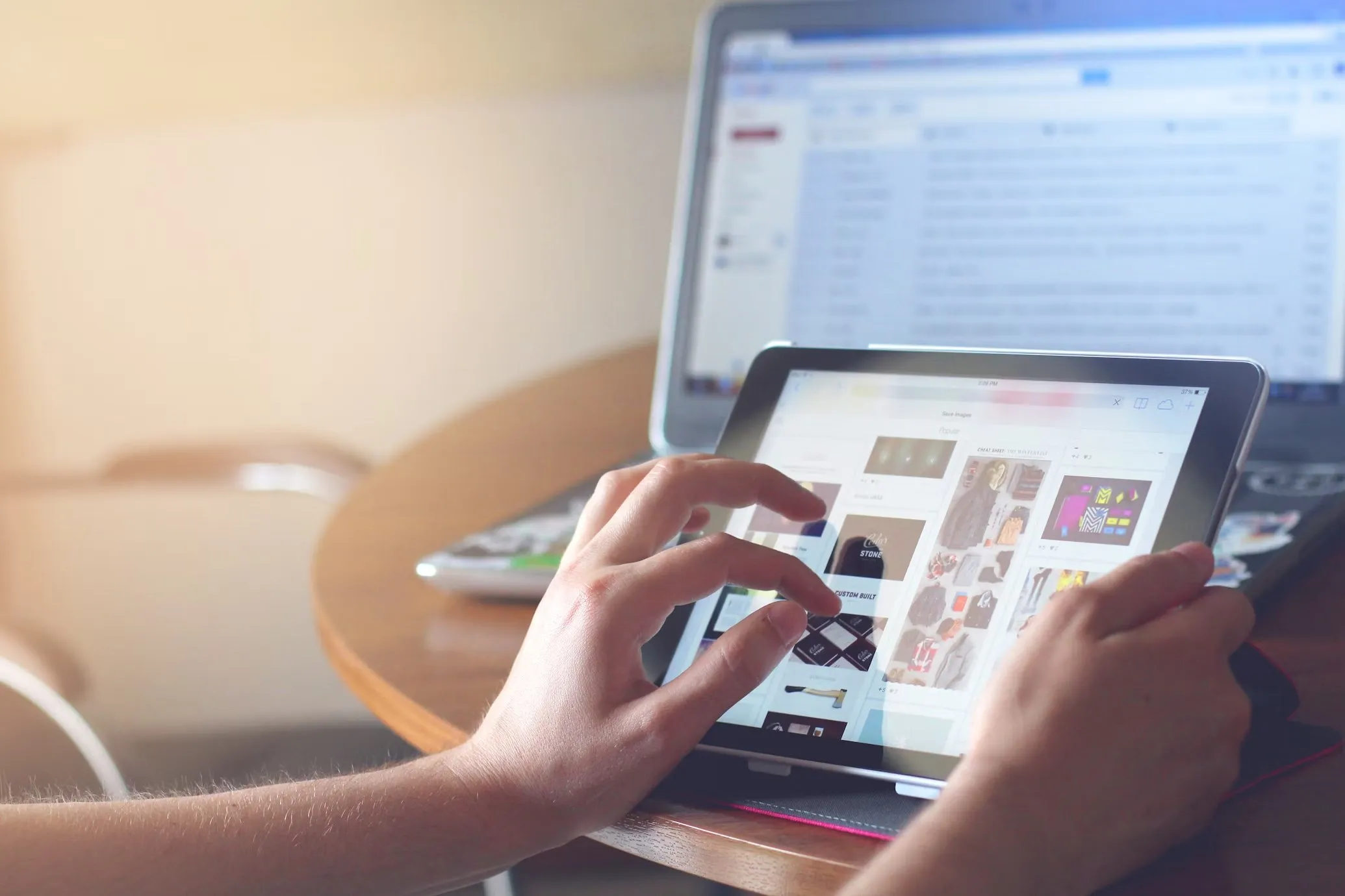 A designer browsing templates on a tablet in front of a laptop